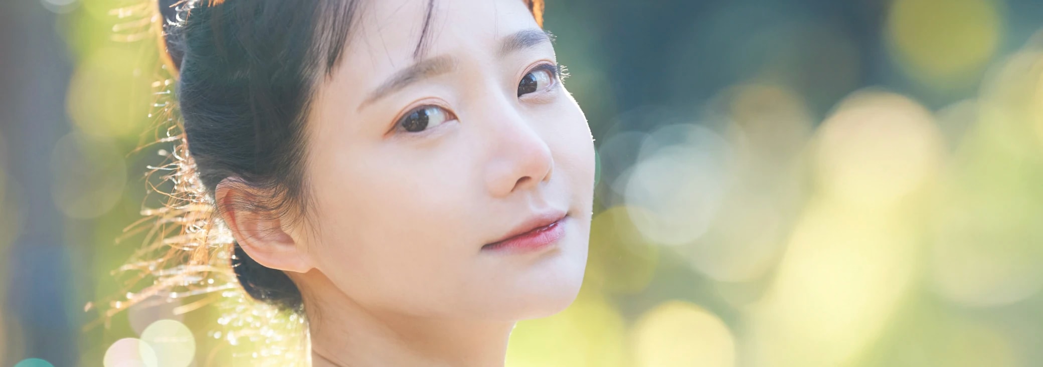 明るめのブラウン系の髪色をして微笑みながら振り返っている女性