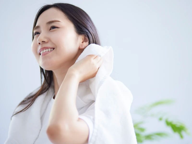 髪をタオルで拭きながら微笑んでいる女性