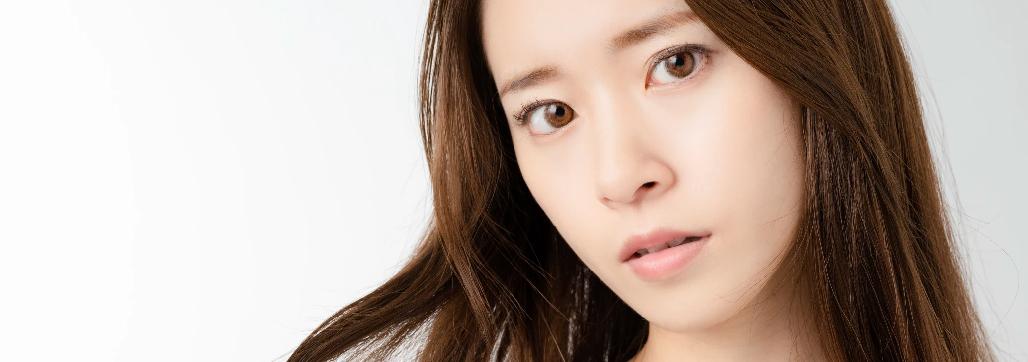 毛先をつまみながら不安そうな表情をしている女性