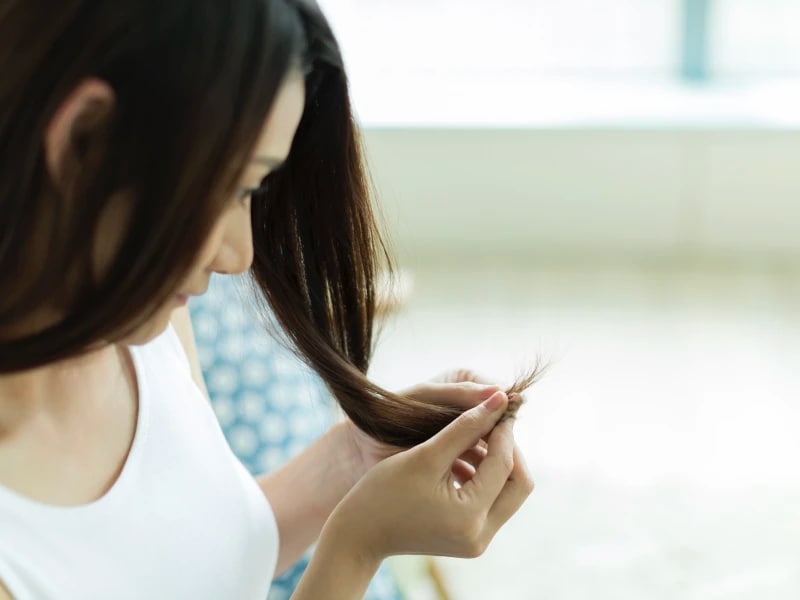 毛先をつまんで見つめている女性