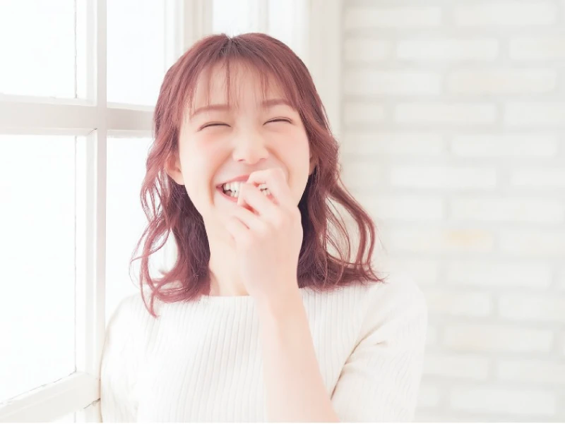 暗めのピンクの髪色をして笑っている女性