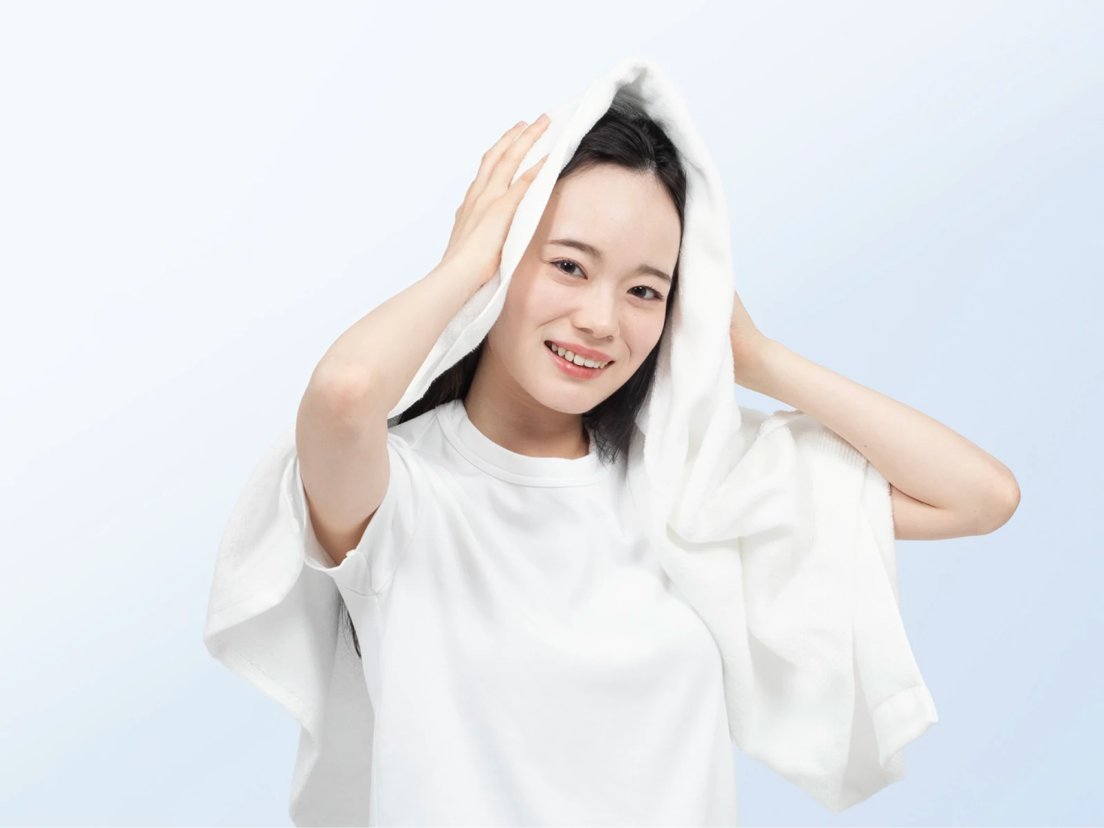洗髪後にタオルで髪を拭いている笑顔の女性