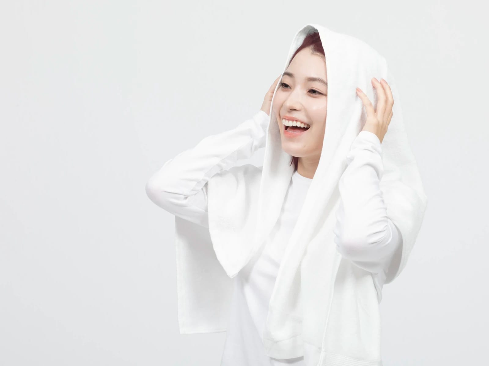 洗髪後にタオルで髪を拭いている笑顔の女性