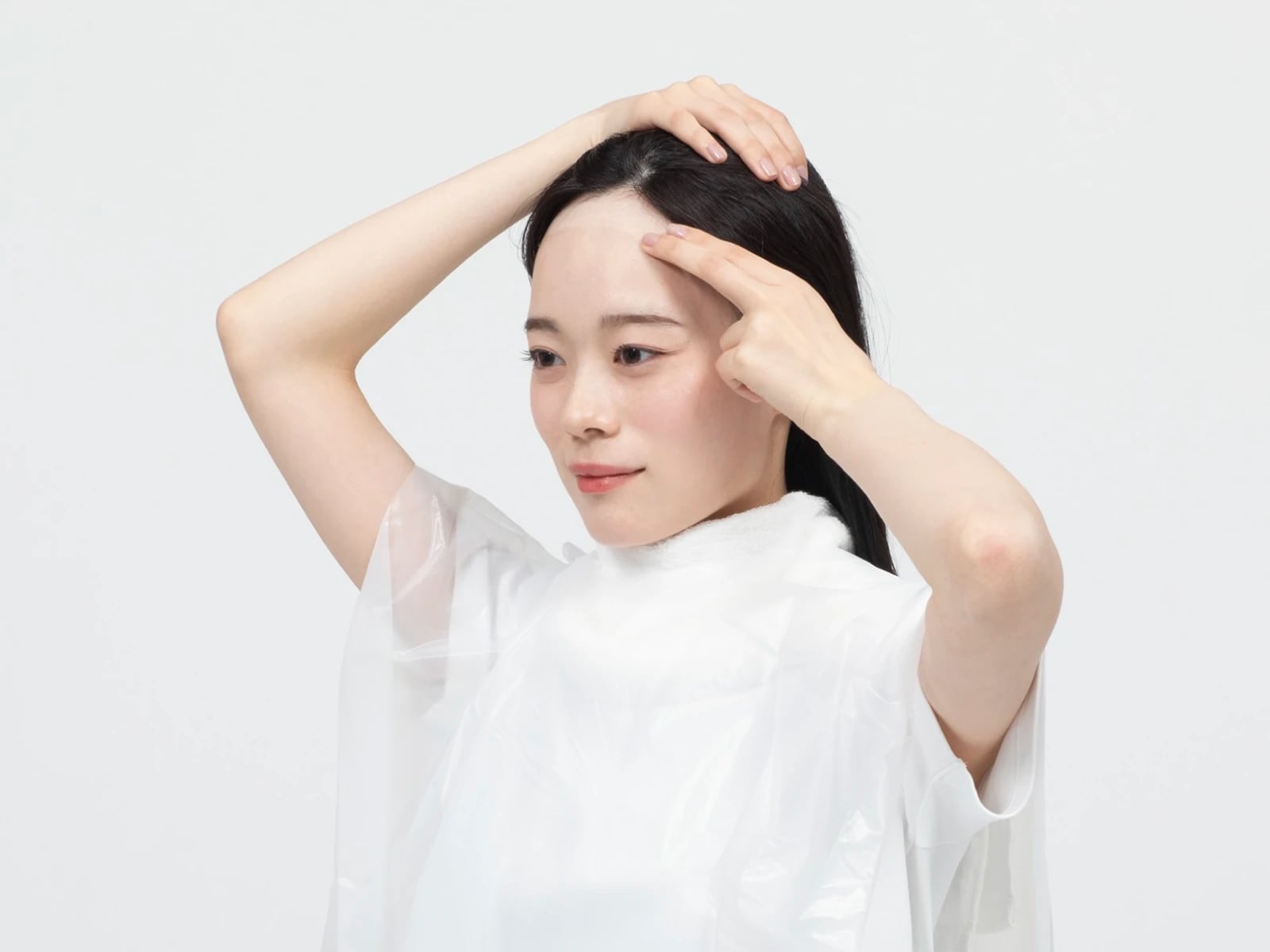 ケープをして髪の生え際に保護クリームを塗っている女性