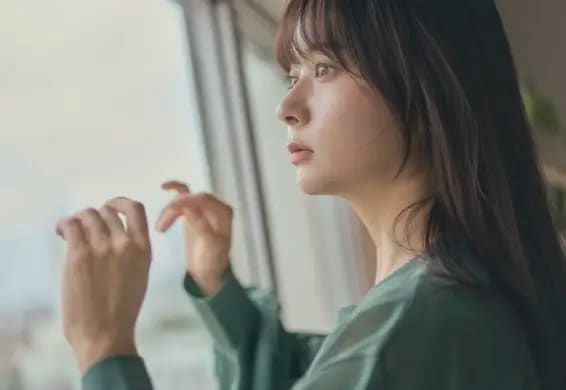 グレージュの髪色をして窓の外を眺めている女性