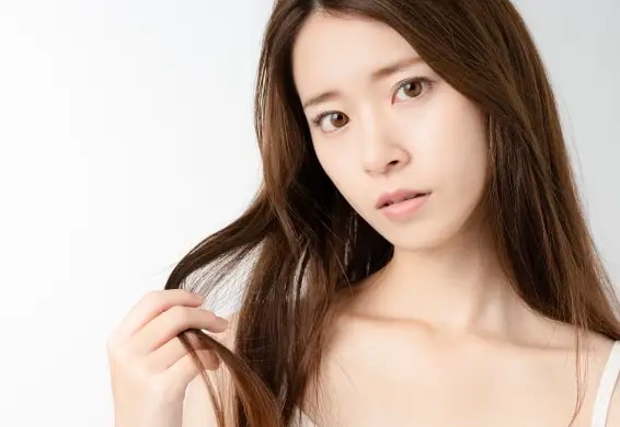 毛先をつまみながら不安そうな表情をしている女性